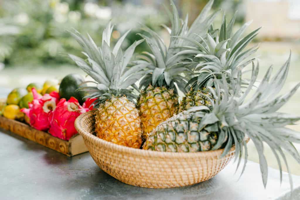 Fresh tropical fruit display featuring ripe pineapples and dragon fruit in a woven basket. Ideal for restaurant websites, organic food blogs, and travel articles focusing on Southeast Asian cuisine